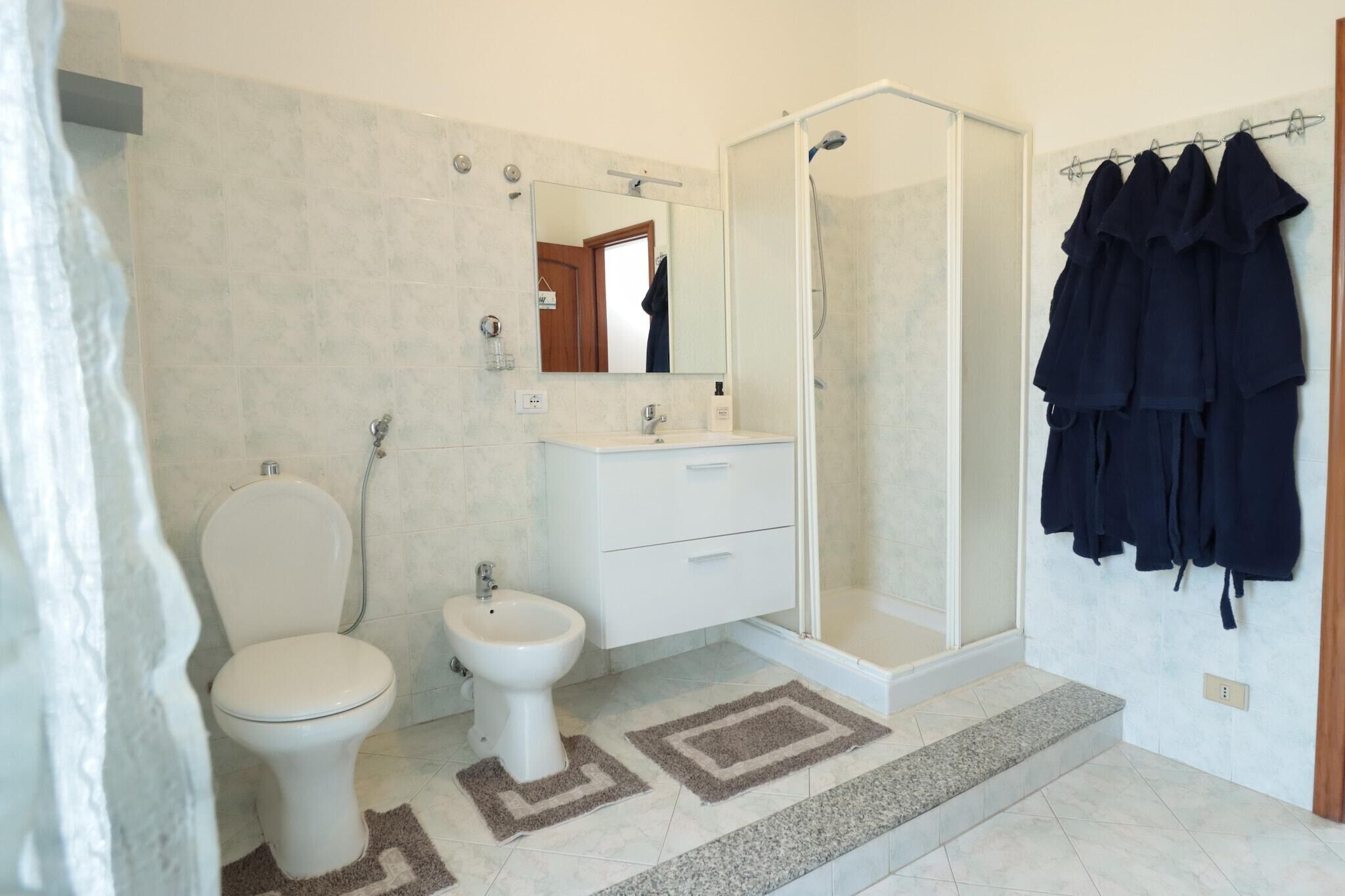 Une salle de bain équipée de toilettes, d’un bidet, d’un lavabo et d’une douche. Des serviettes sont accrochées au mur.