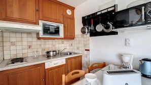 A compact kitchen with wooden cabinets, a built-in oven, a microwave, a toaster, and a coffee maker.