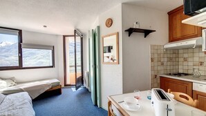 A compact kitchen with a dining area, a bed, and a view of the outdoors.