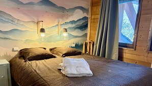 A bedroom with a bed, a nightstand, a window with curtains, and a mural on the wall. - Spacious apartment for 10, balcony, parking, near slopes (Saint-Martin-de-Belleville)