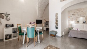 Un comedor acogedor con una mesa redonda, sillas color turquesa y un televisor blanco montado en la pared.
