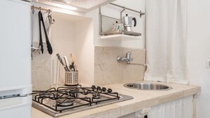 Una cocina con estufa a gas, un fregadero y un tendedero con utensilios.