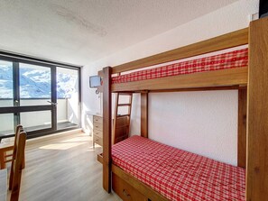 Cozy room with a bunk bed setup, featuring a desk and chair, and a large window offering a view of the surrounding landscape.