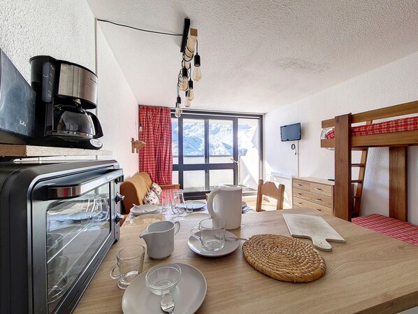 Enjoy a warm meal in this mountain cabin's kitchen, featuring a stove, coffee maker, and dining table with scenic views of snow-capped mountains.