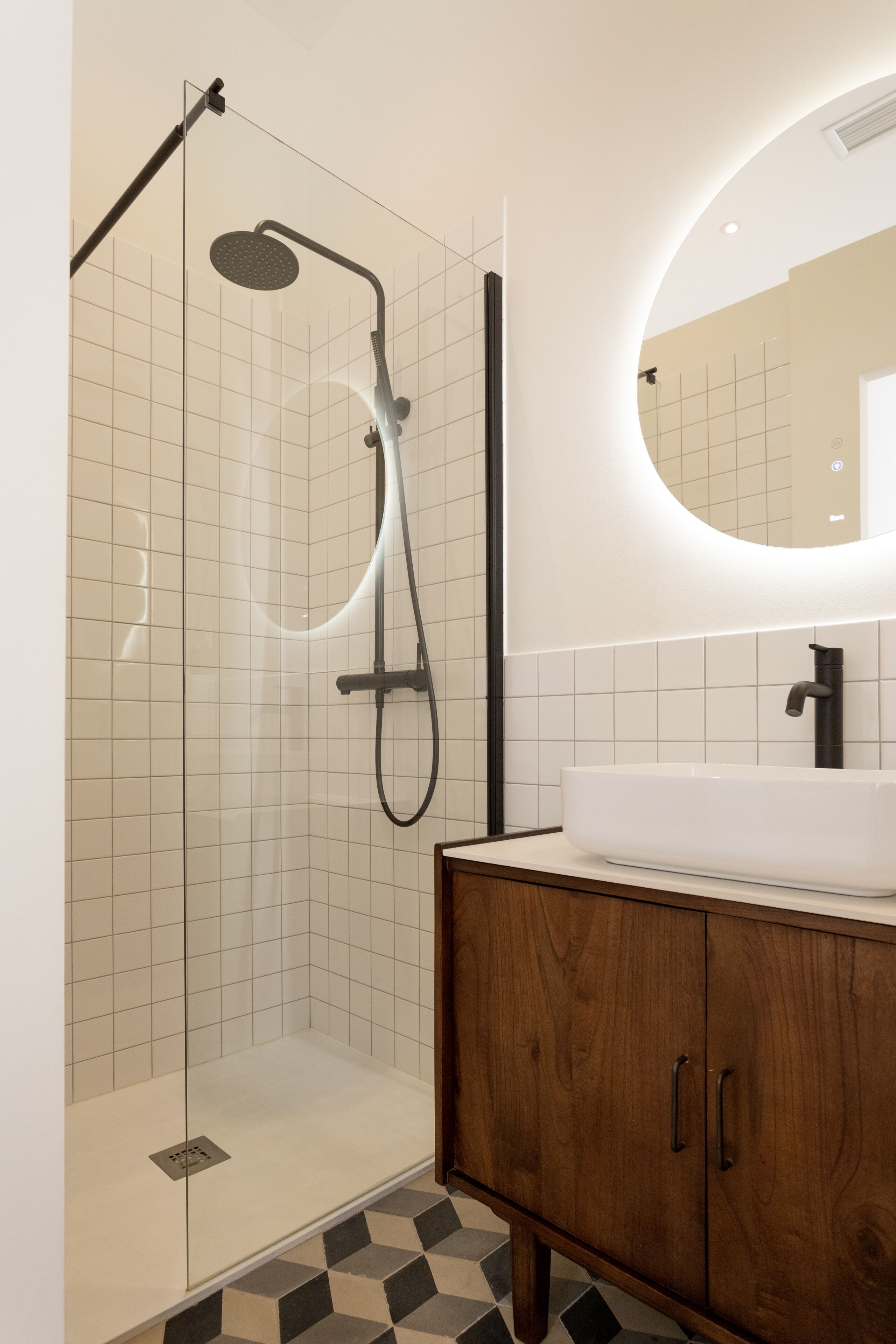 Une salle de bain moderne avec une douche à parois de verre, un meuble-lavabo en bois et un grand miroir.