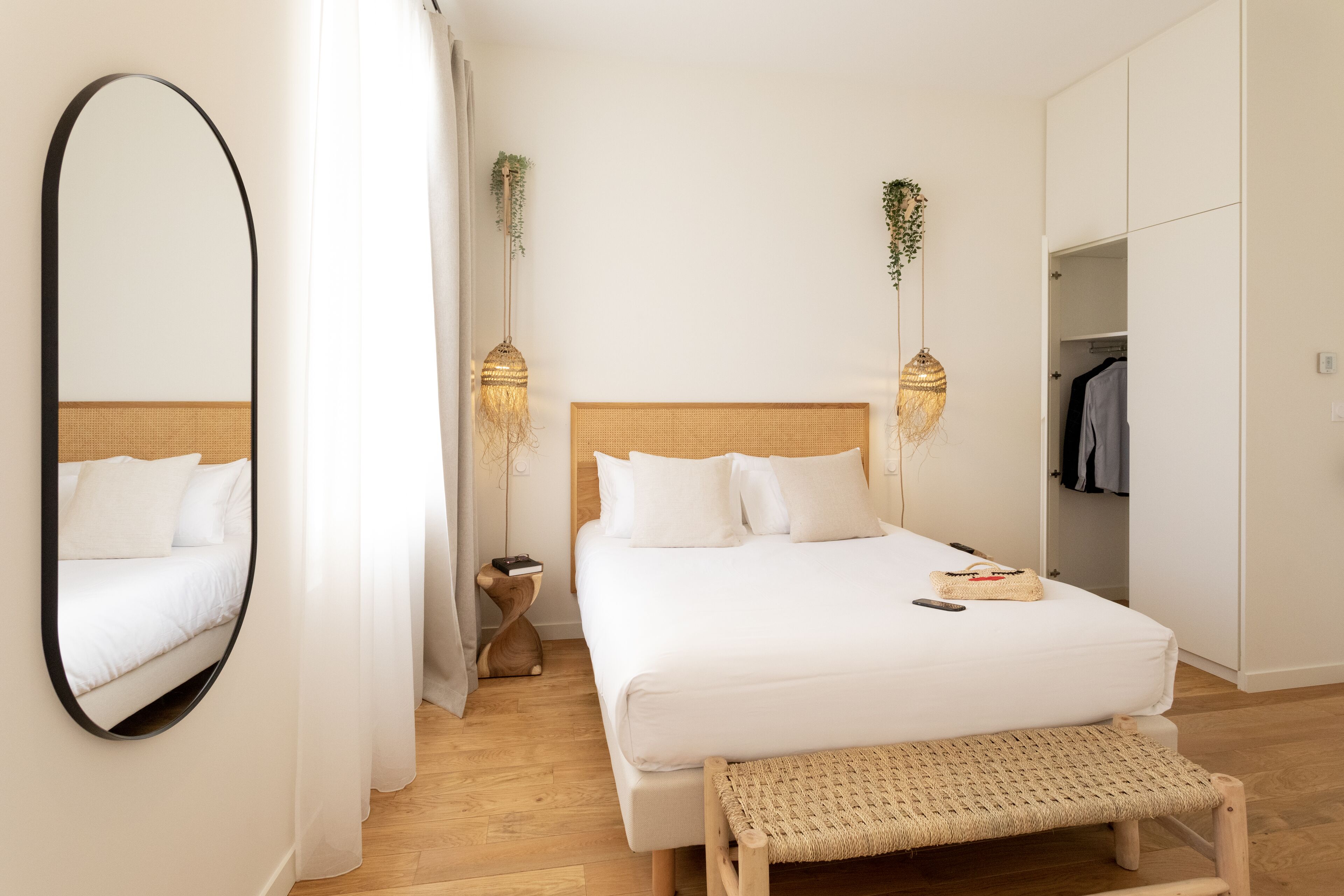A bedroom with a large bed, a bedside table, a mirror, and a wardrobe.