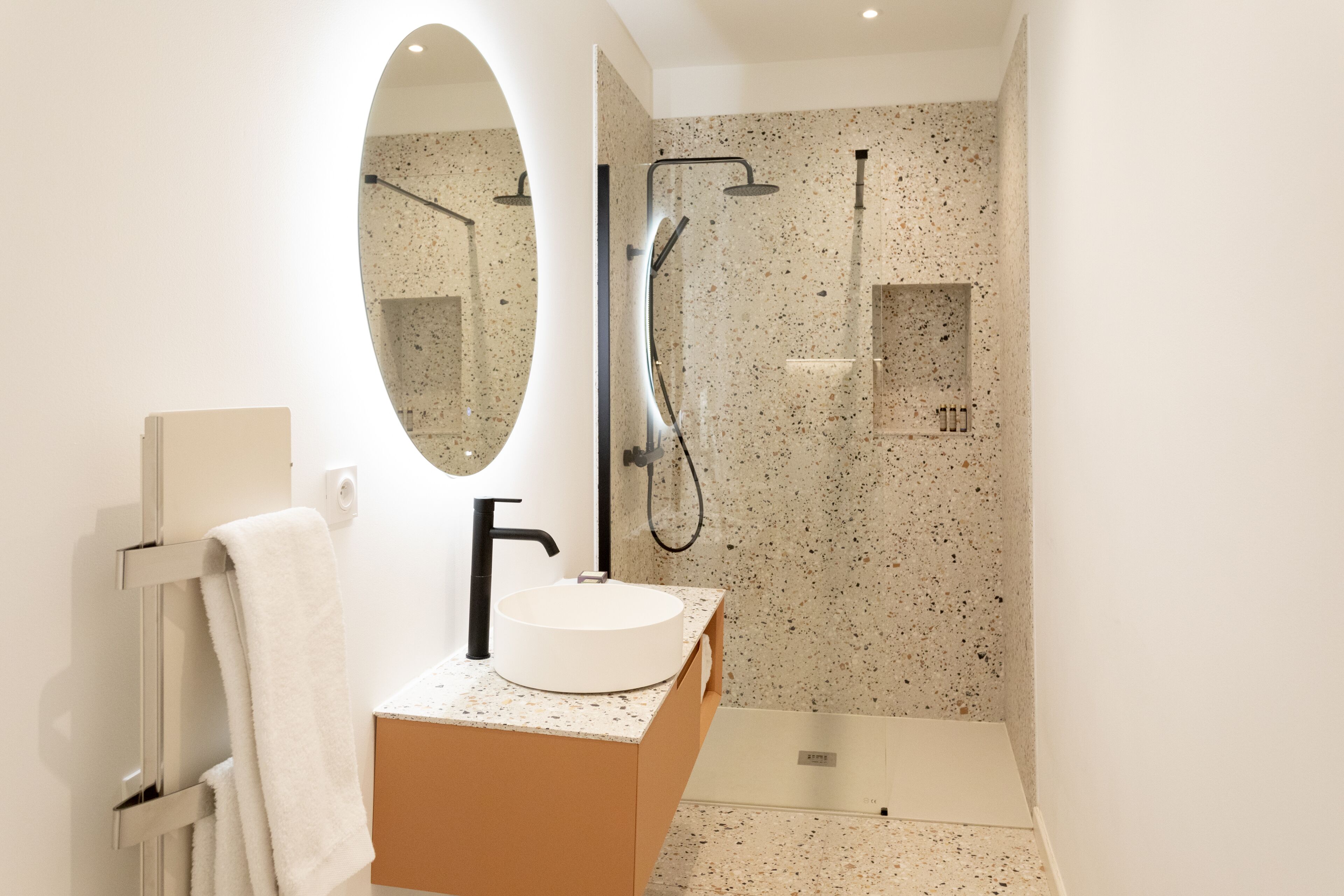 Une salle de bain moderne avec une baignoire sur pieds, un lavabo rond et un miroir à cadre ovale.