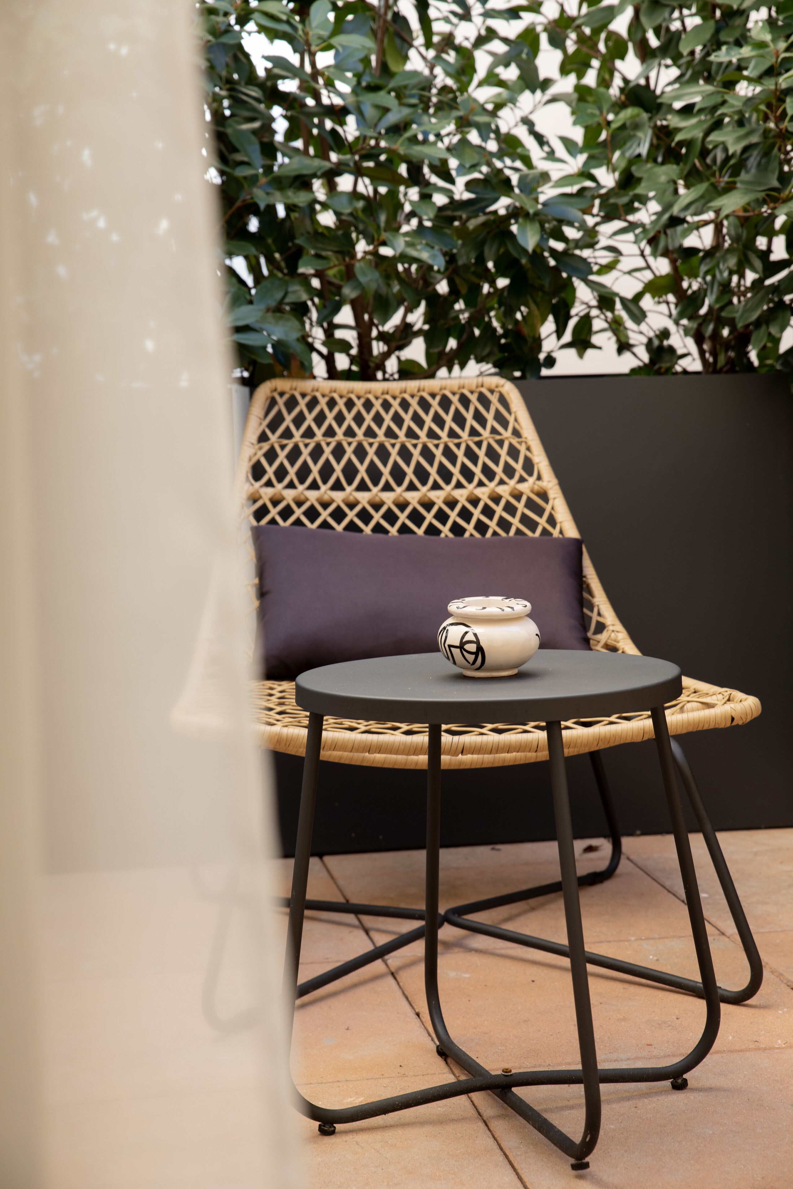 A wicker chair with a cushion and a small table with a decorative item.