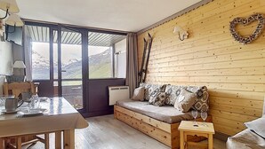 A cozy room with a wooden wall, a sofa, a small table, and a view of the outdoors.