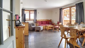 Una habitación acogedora con un sofá de madera, una mesa de comedor con sillas y una cafetera.