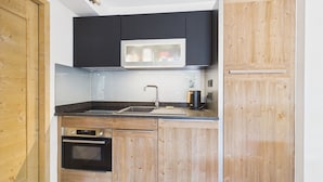 A compact kitchen with a built-in oven, a microwave, and a sink.