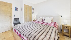 A bedroom with a bed, a chair, a wardrobe, and a bedside table.