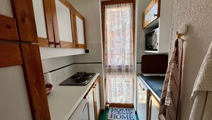 Una cocina compacta con armarios de madera, estufa y microondas.