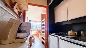 Cuina compacta amb cafetera, nevera petita i un rentaplat.