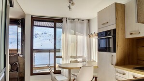 Cozinha moderna com área de jantar, janelas amplas e vista para uma paisagem nevada.