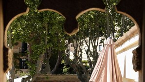Una terrazza esterna con mobili in vimini, un tavolo e un ombrellone.