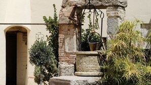 Un cortile con una fontana in pietra, piante in vaso e una lampada a energia solare.