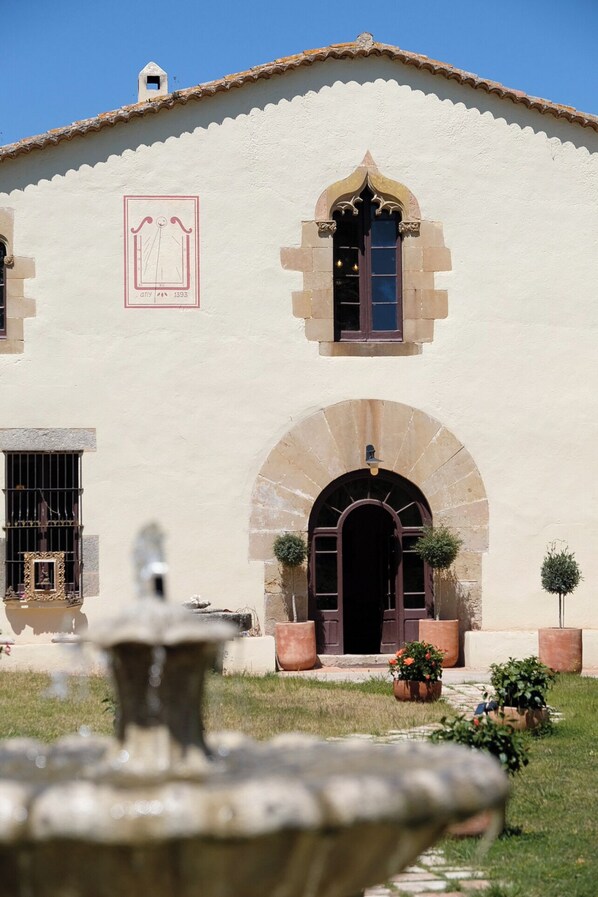 A building with a tiled roof, a central arched entrance, and a small window with a decorative frame.