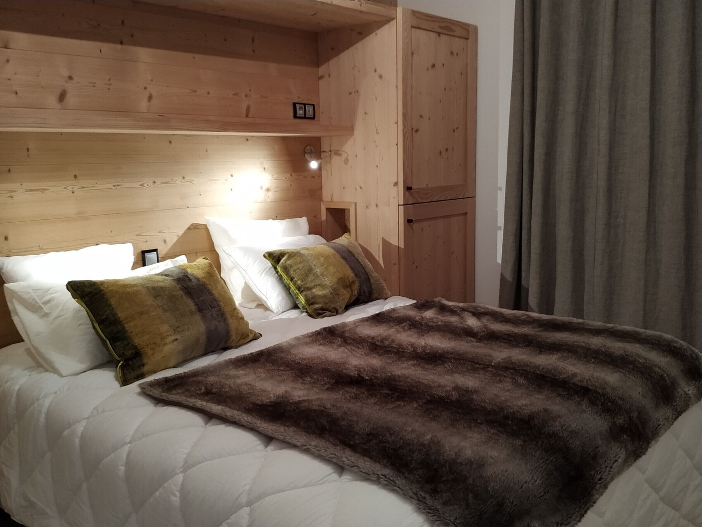 Un dormitorio de cabaña de madera con cama, almohadas y una manta de piel.