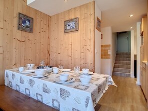 A dining area with a long table set for a meal, wooden walls, and framed pictures on the wall.