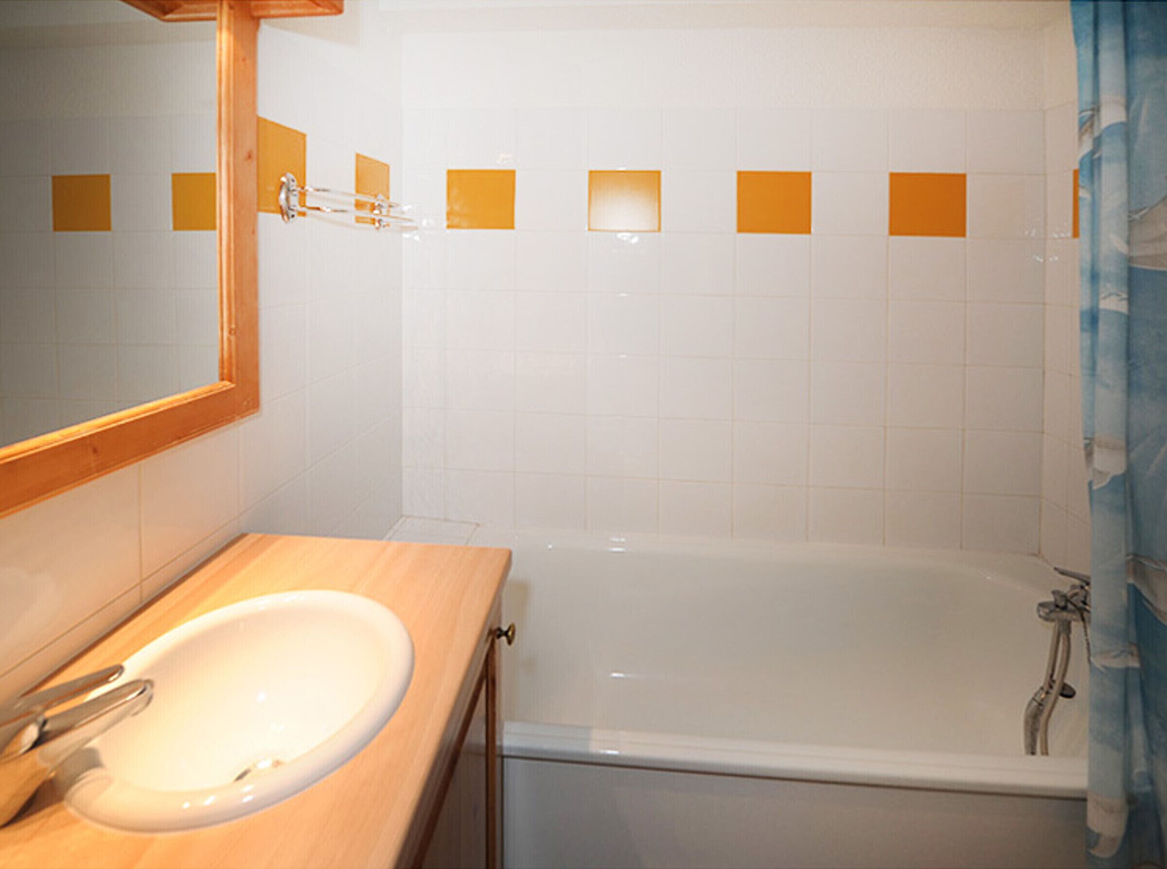 A bathroom with a white sink, mirror, and bathtub.