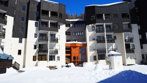 A multi-story hotel with balconies, a central entrance, and snow-covered surroundings. - Cozy studio at the foot of the slopes, balcony, pets allowed (Les Menuires)