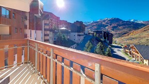 Uma varanda com vista para uma paisagem montanhosa e edifícios.