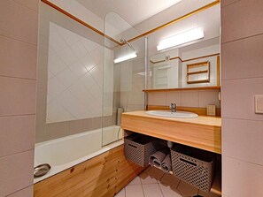 Ein modernes Badezimmer mit Duschkabine aus Glas, einem Holzwaschtisch und einem großen Spiegel.
