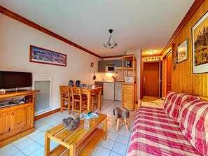 A cozy living room with a wooden sofa, a TV, and a dining area with a table and chairs. - Bright Apartment 6 pers · Near slopes · Southwest terrace (Saint-Martin-de-Belleville)
