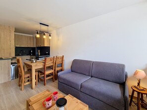 A compact living space with a sofa, dining table, chairs, and a kitchenette.