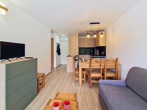 Ein stilvoller Wohnraum mit Flachbildfernseher, Esstisch aus Holz und einer Couch.