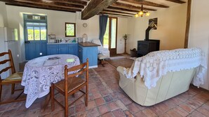 Una habitación acogedora con techo de madera, kitchenette, zona de comedor con mesa y sillas, y un sofá.