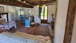 Una cocina rústica con techo de madera, un comedor con mesa y sillas, y una zona de estar acogedora con un banco.