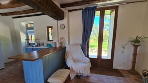 Cocina acogedora con mostrador de madera, alacenas azules, una banca y vistas a un jardín por una puerta.