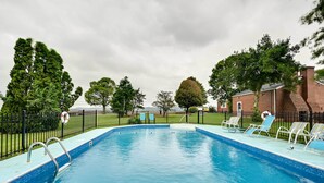 Ein rechteckiger Pool mit blauer Fliesenbordüre, umgeben von einem schwarzen Metallzaun.