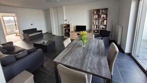 Un salon moderne comprenant une table à manger, des canapés, une bibliothèque et une cheminée.