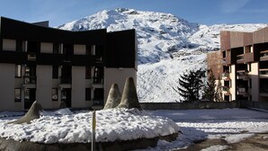 Montanha coberta de neve ao fundo, com edifícios modernos em primeiro plano.