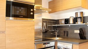Cozinha moderna com eletrodomésticos de aço inoxidável, armários de madeira e forno embutido.