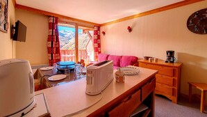 Eine gemütliche Küche mit Esstisch, Kaffeemaschine und Bergblick durch das Fenster.