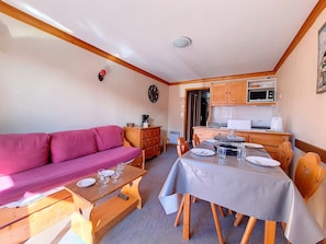 A compact living space with a sofa, a dining table, and a kitchenette.