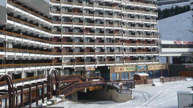 Un hôtel à plusieurs étages doté de balcons, d’un télésiège et offrant une vue sur la montagne.