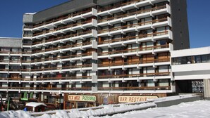 Un hôtel à plusieurs étages doté de balcons, d’un bar et d’une pizzeria.