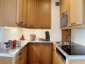 Una cucina con mobili in legno, un forno a microonde, una macchina da caffè e un lavandino.