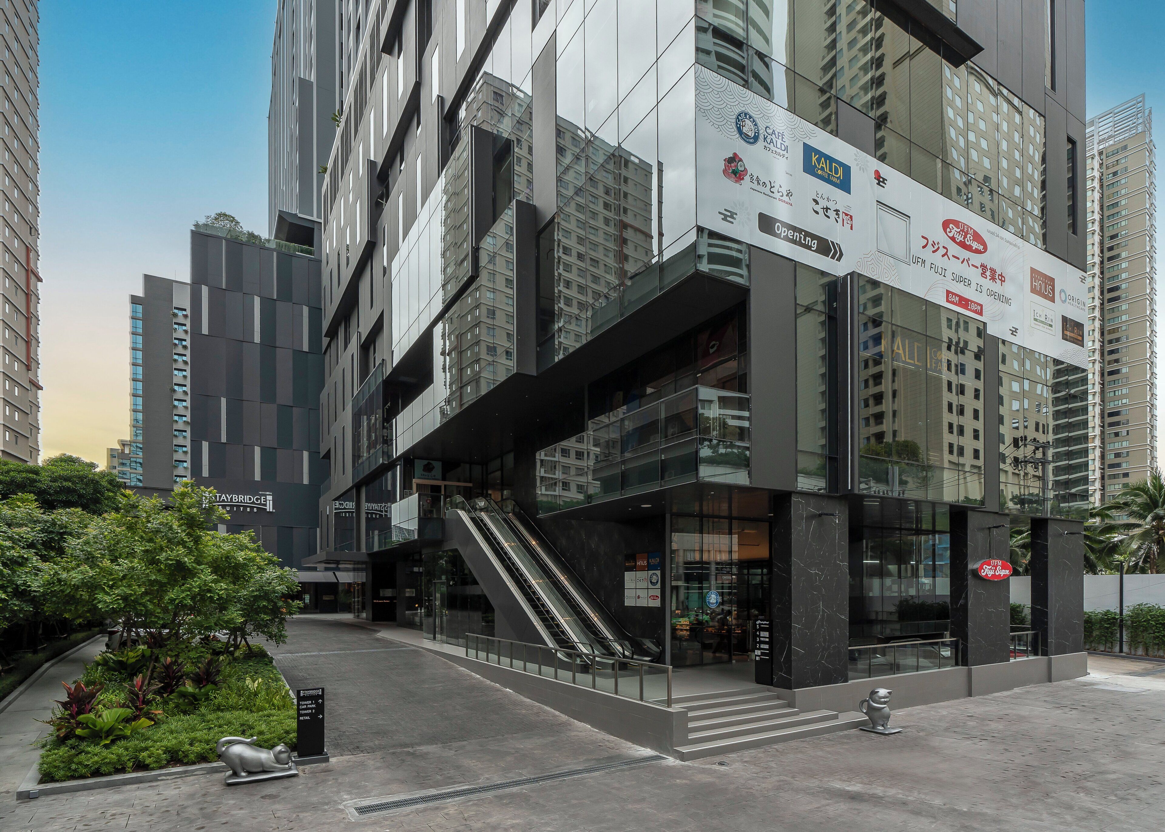 A modern building with a glass facade, a visible staircase, and signage for a cafe and a hotel.