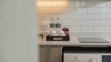 Una cocina con salpicadero de azulejos blancos, una cafetera, dos botellas de agua y una caja de pañuelos.