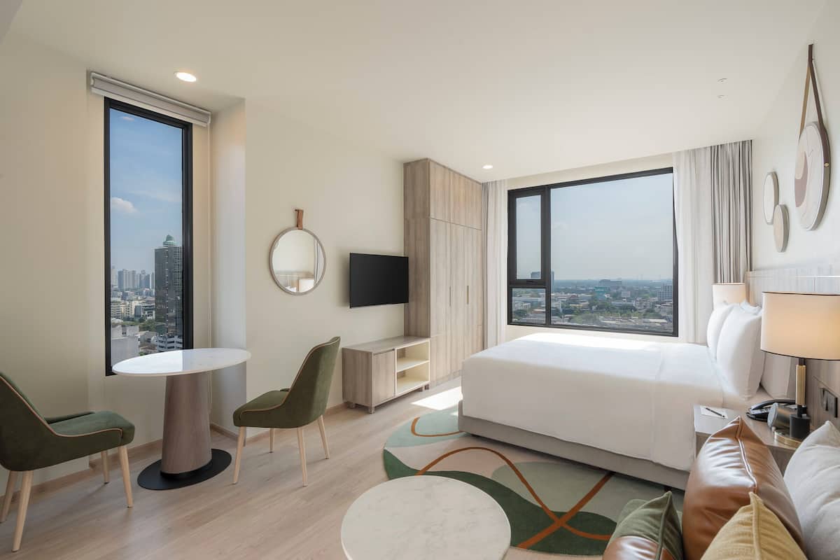 Une chambre d’hôtel moderne dotée d’un grand lit, d’un bureau, d’une chaise, d’une télévision et offrant une vue sur la ville.