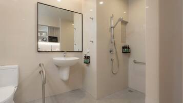 A modern bathroom with a sink, mirror, shower, and toilet.