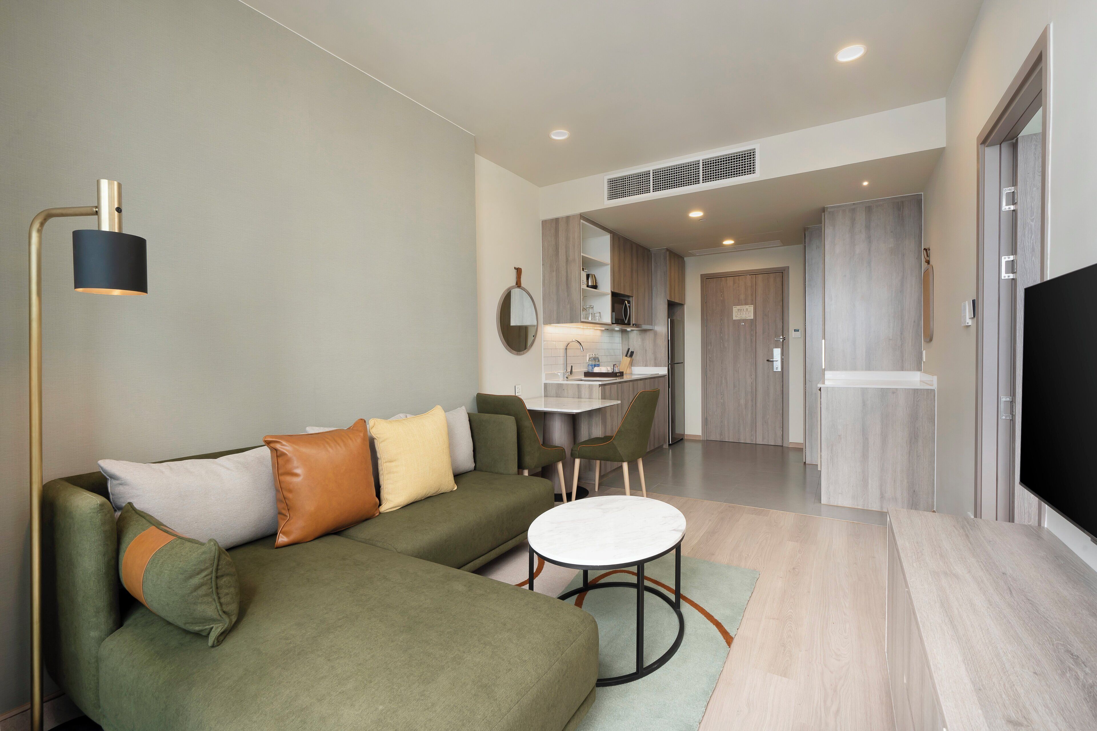 A modern living room with a sectional sofa, a round coffee table, and a flat-screen TV.