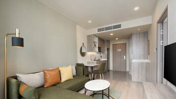 A modern living room with a sectional sofa, a round coffee table, and a flat-screen TV.
