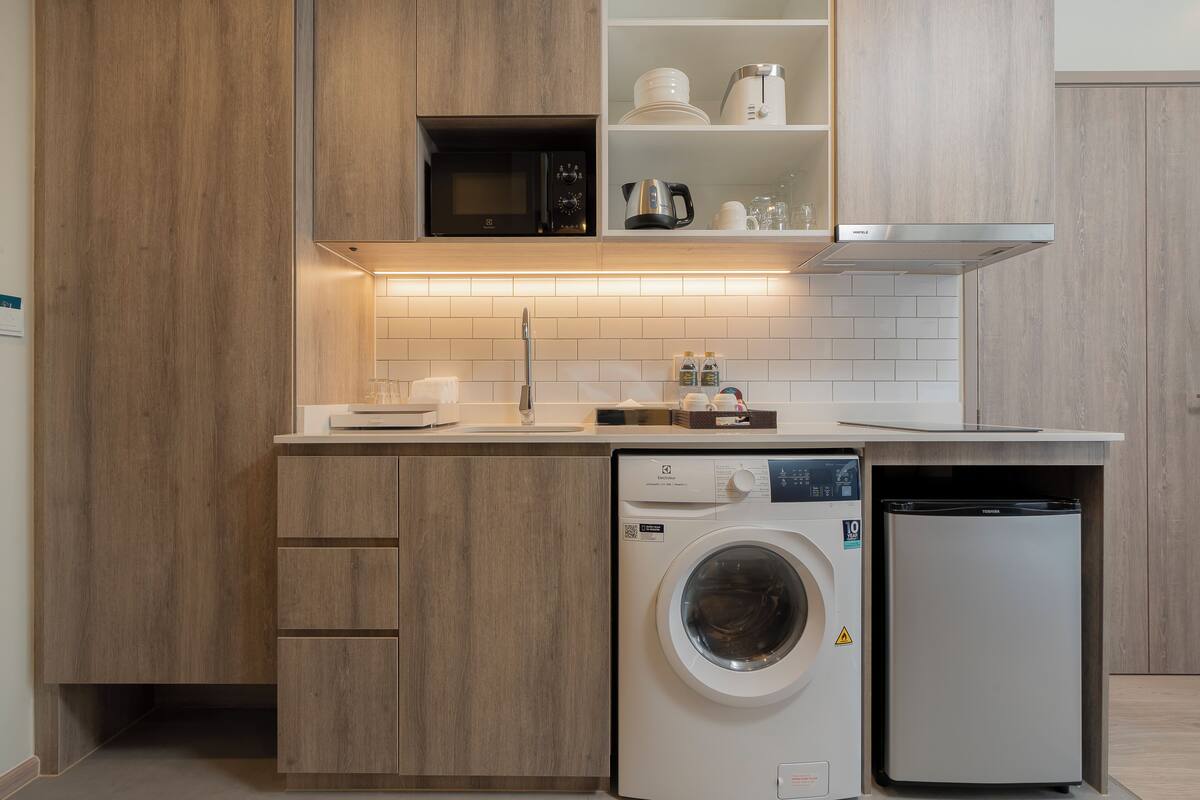 Une cuisine compacte avec des meubles en bois, un four à micro-ondes encastré, un lave-vaisselle et un réfrigérateur.